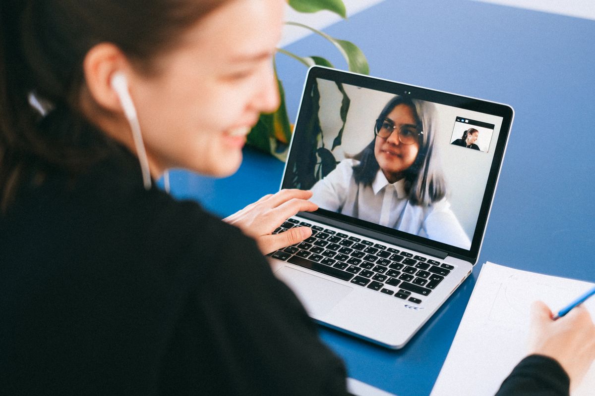 Two people speaking by video call while taking notes